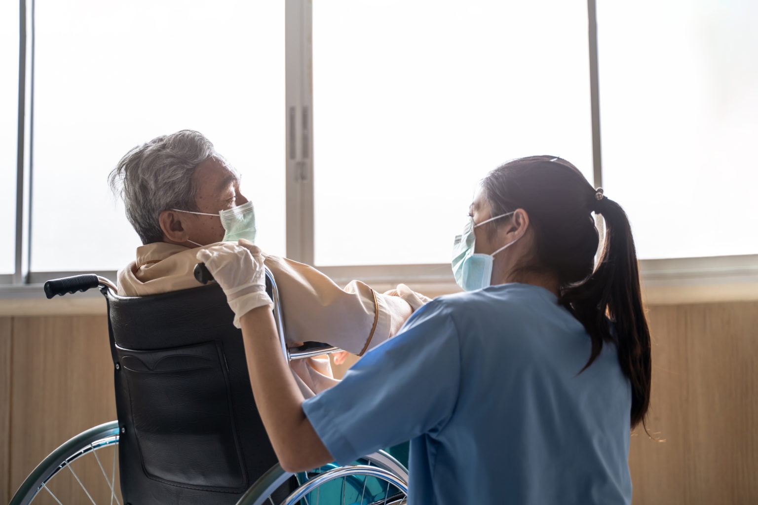 Nurse taking care of mature patient in front of window