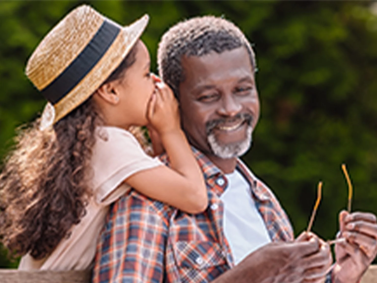Granddaughter whispering into grandfather's ear
