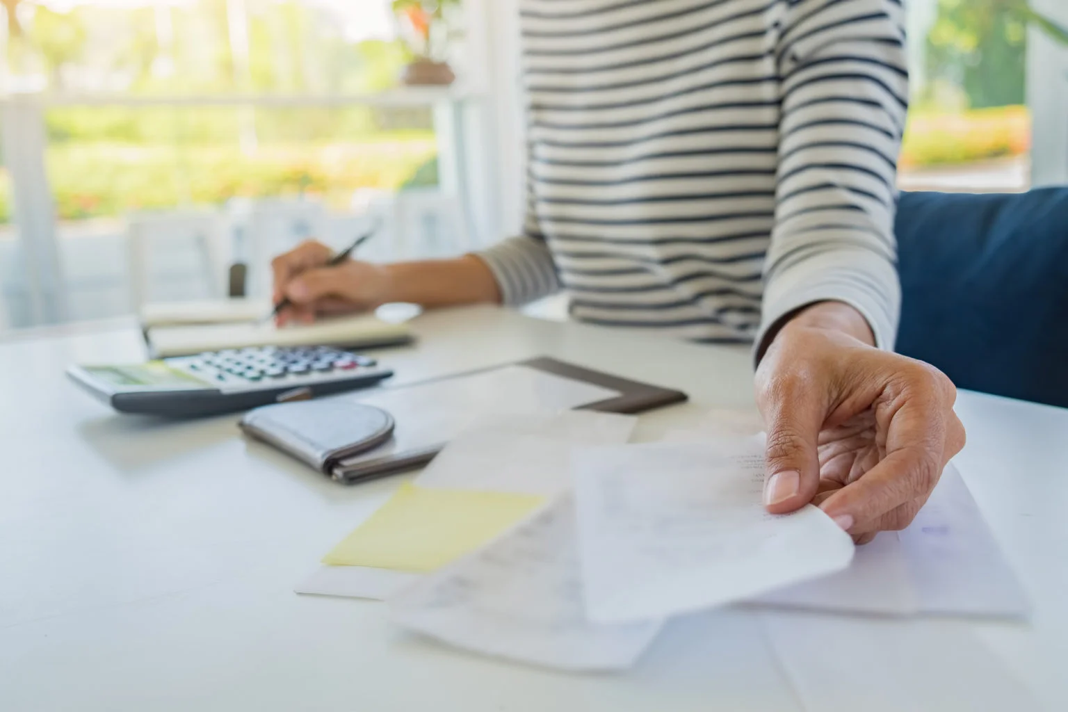 Woman using calculator to calculate bills at the table in office.