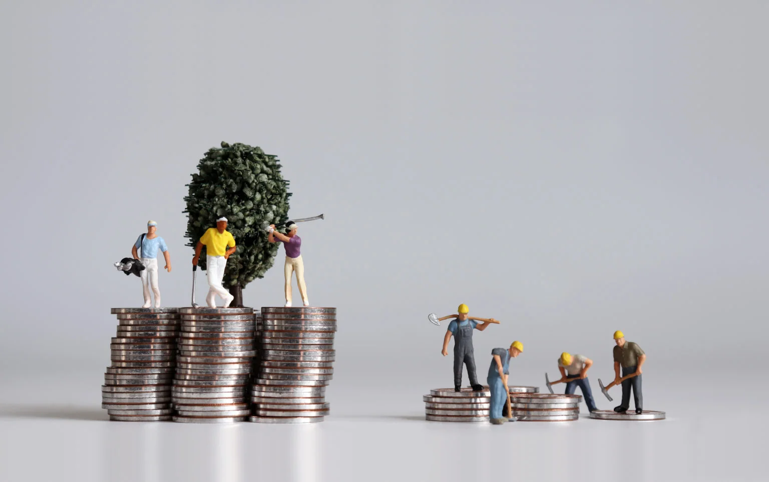 Miniature people and pile of coins. Concepts about the lives of the rich and the poor