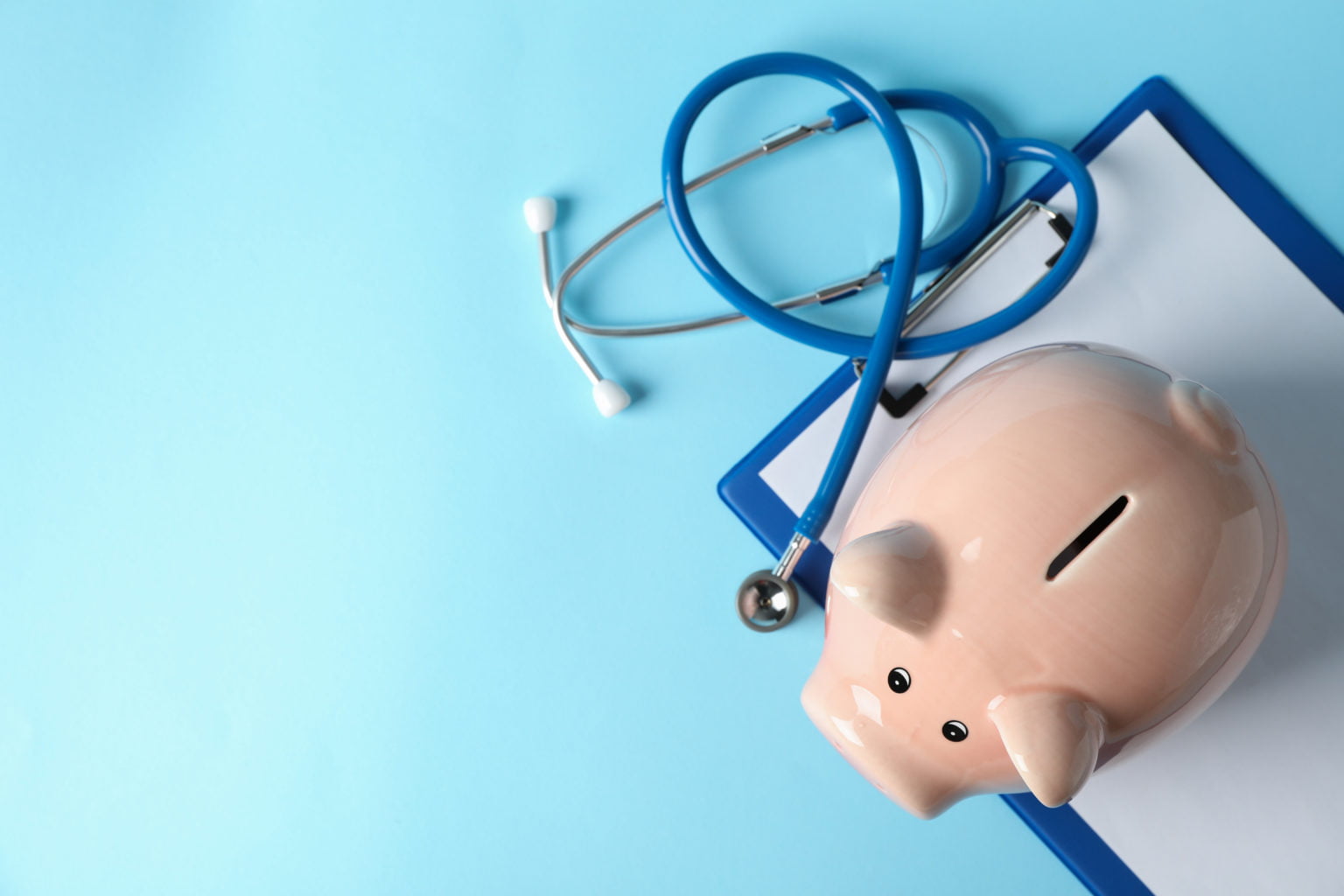 Stethoscope and piggy bank on blue background