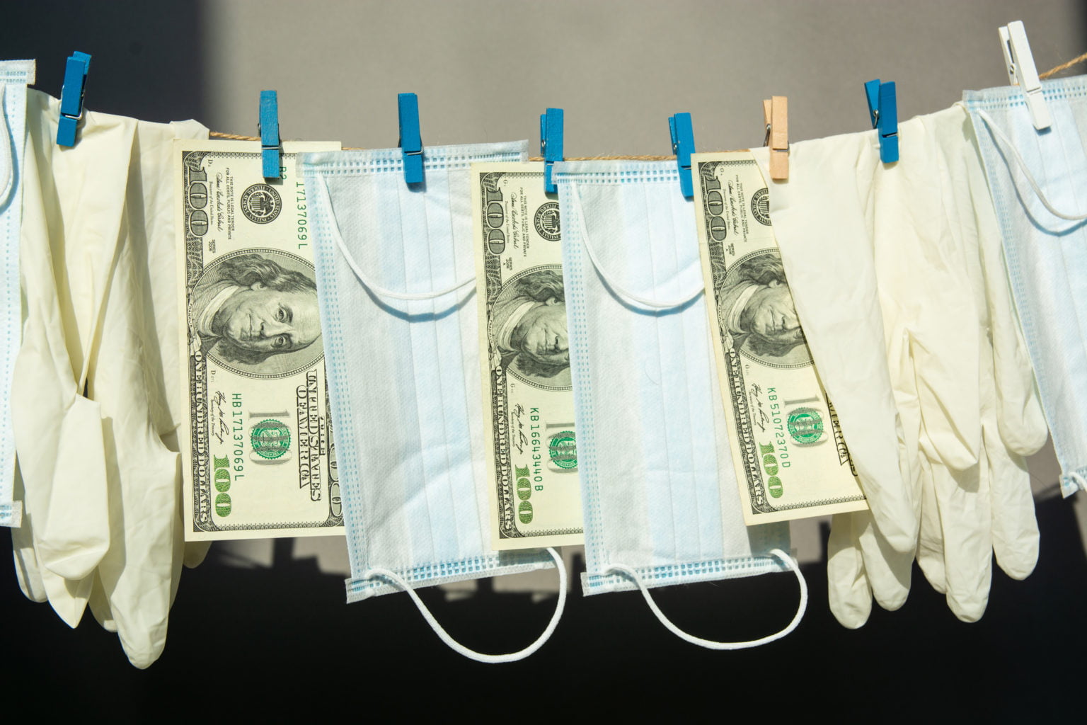 100 dollar bills, COVID masks and latex gloves on a clothes line