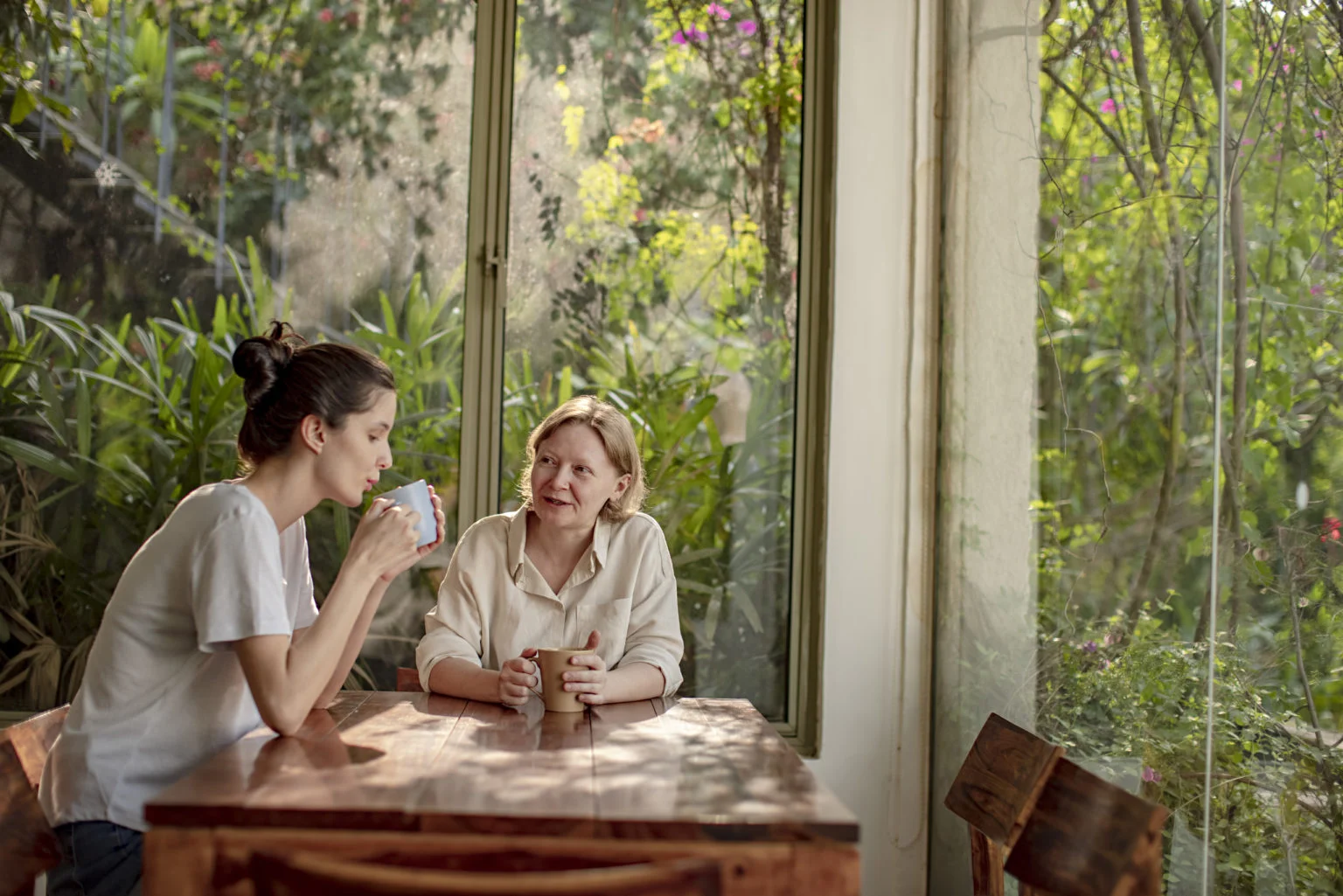 Mature woman drinking cup of tea with her daughter at home