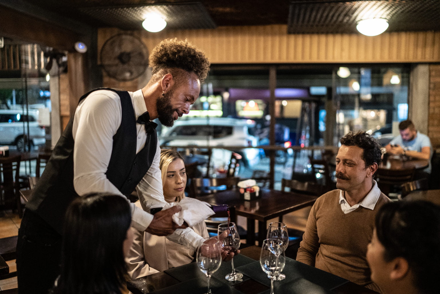 Waiter serving wine to customers at a bar