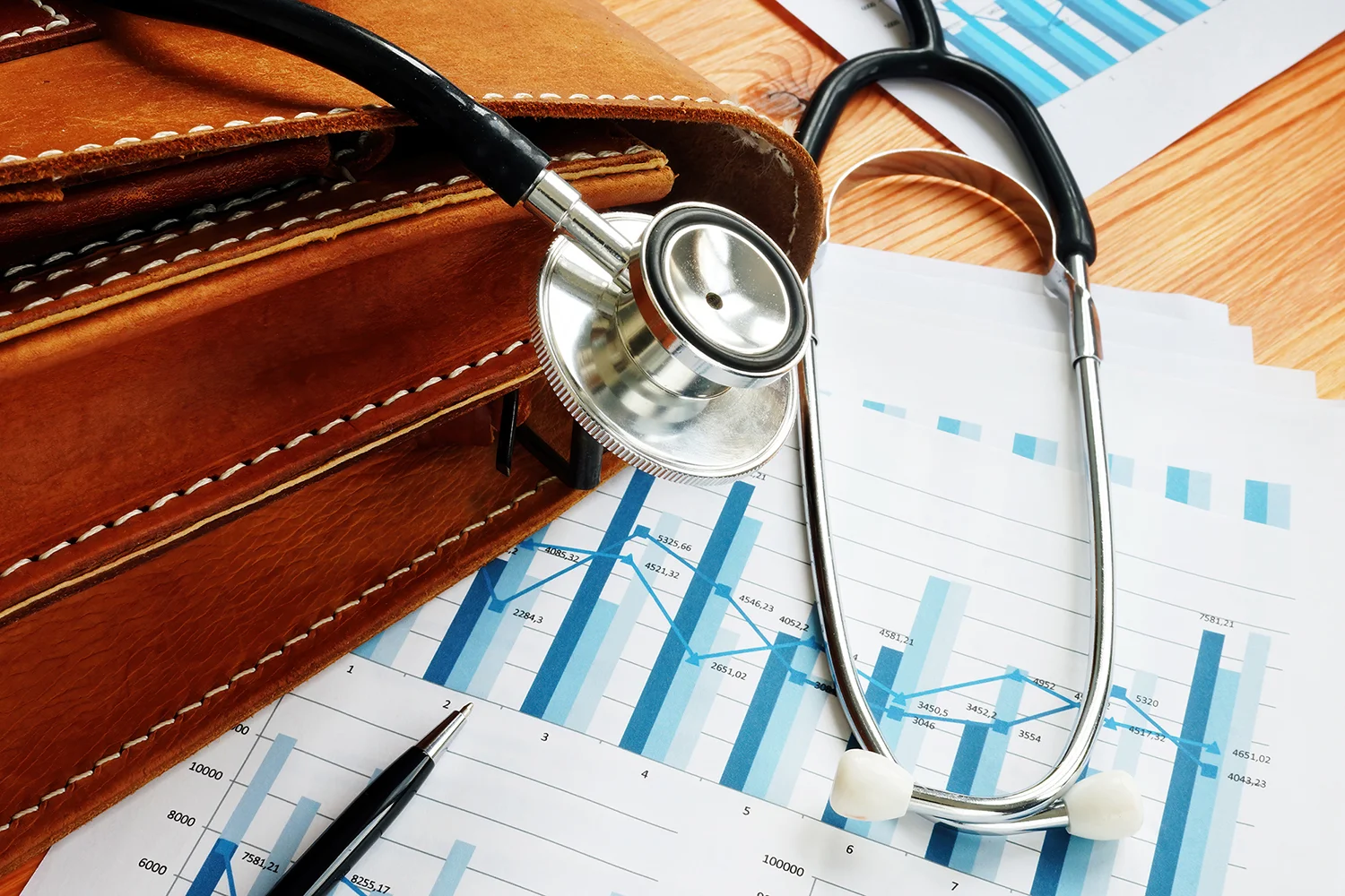 Business briefcase, stethoscope and financial market charts