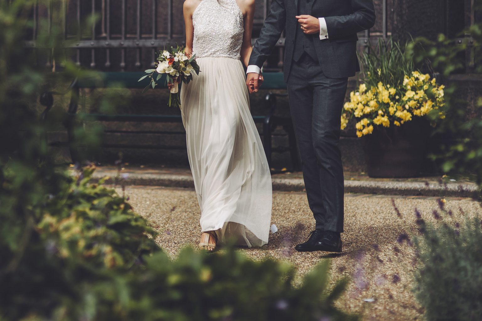 Lower half of a bride and groom holding hands