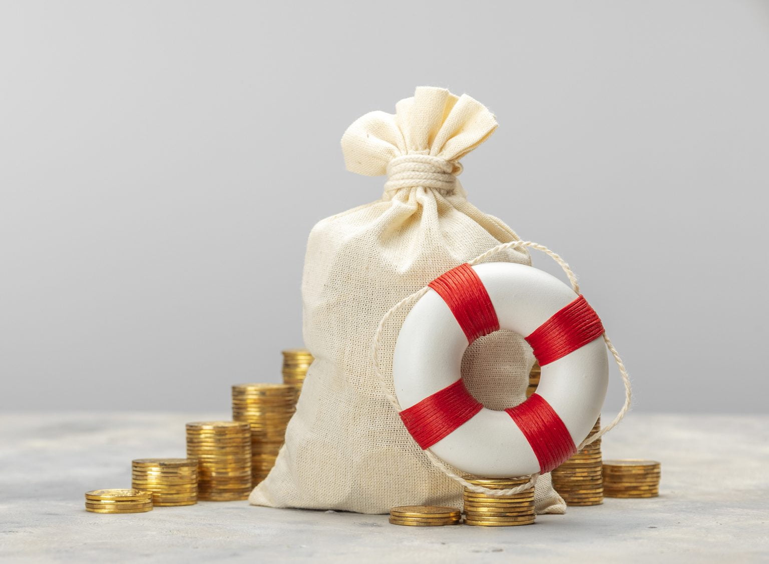 Money bag with coins and a lifebuoy on a gray background
