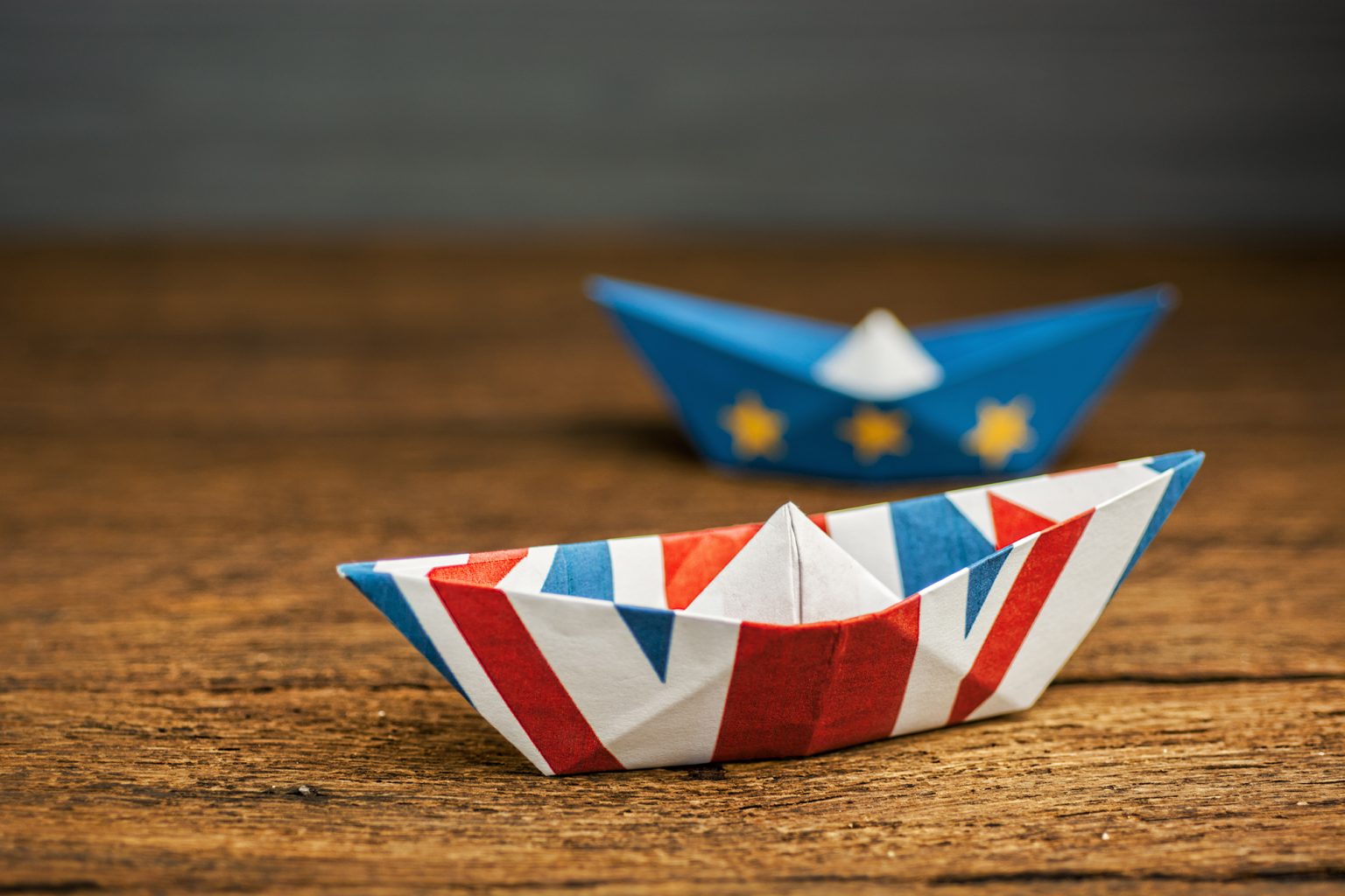Paper ships from the flags of the European Union and the UK on a blue background