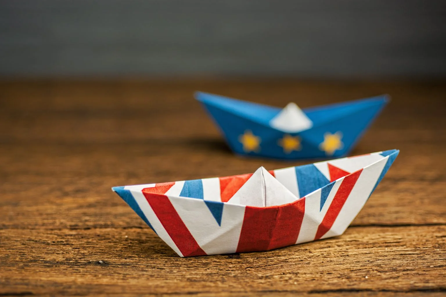 Paper ships from the flags of the European Union and the UK on a blue background