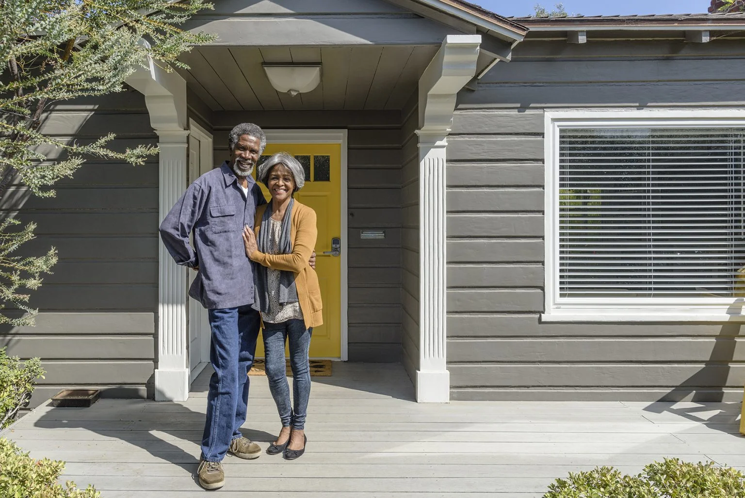 Senior couple smiling outside their home