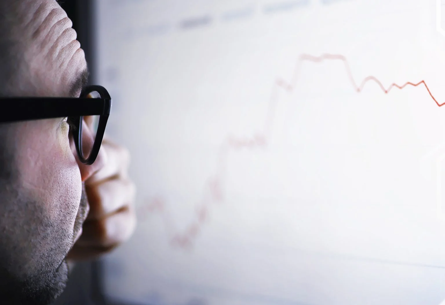 A businessman is looking at a graph on a monitor