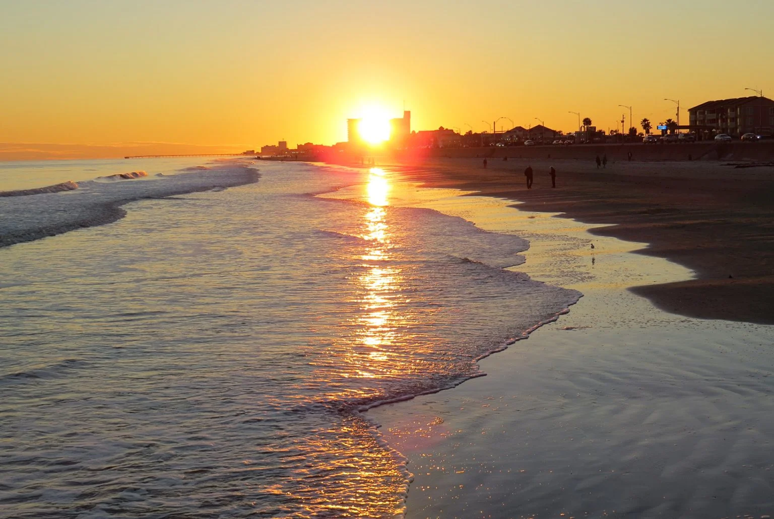 A gorgeous sunset in Galveston Island in Texas while waves gently wash ashore