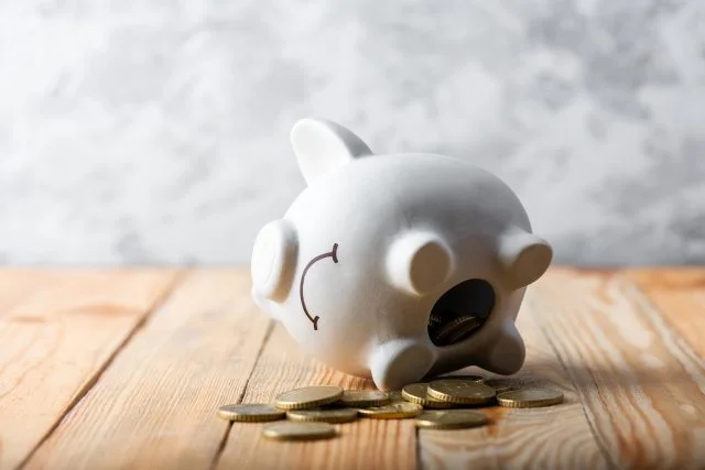 A sad piggy bank tipped over on its side with coins coming out