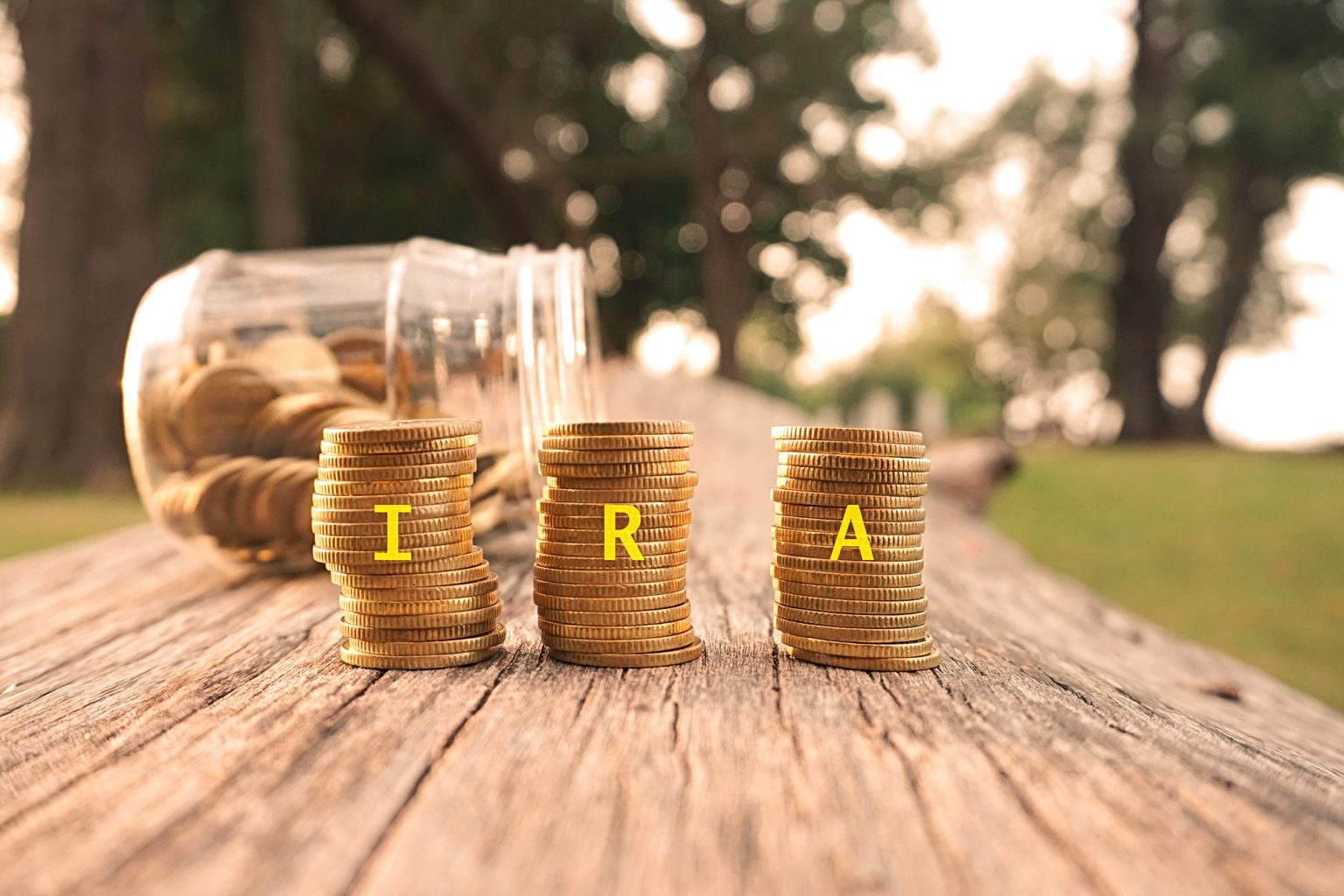 Close up of stacking gold coins written IRA on nature background and natural lighting