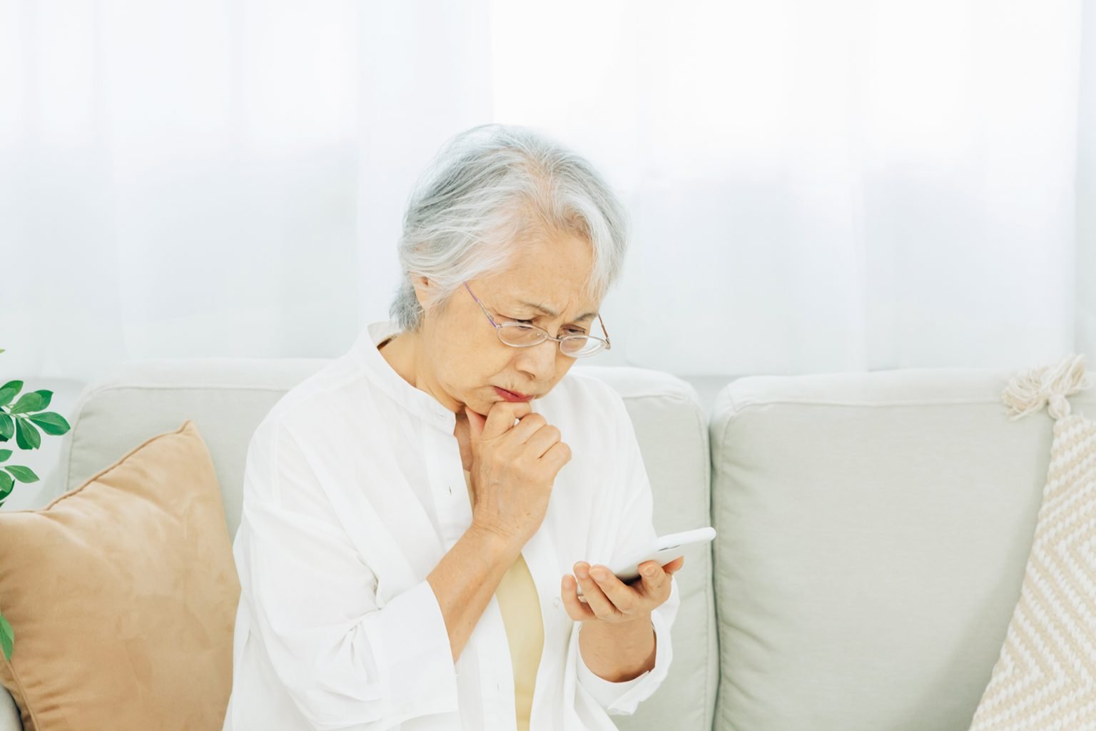 Elderly woman looking worried and looking at her phone