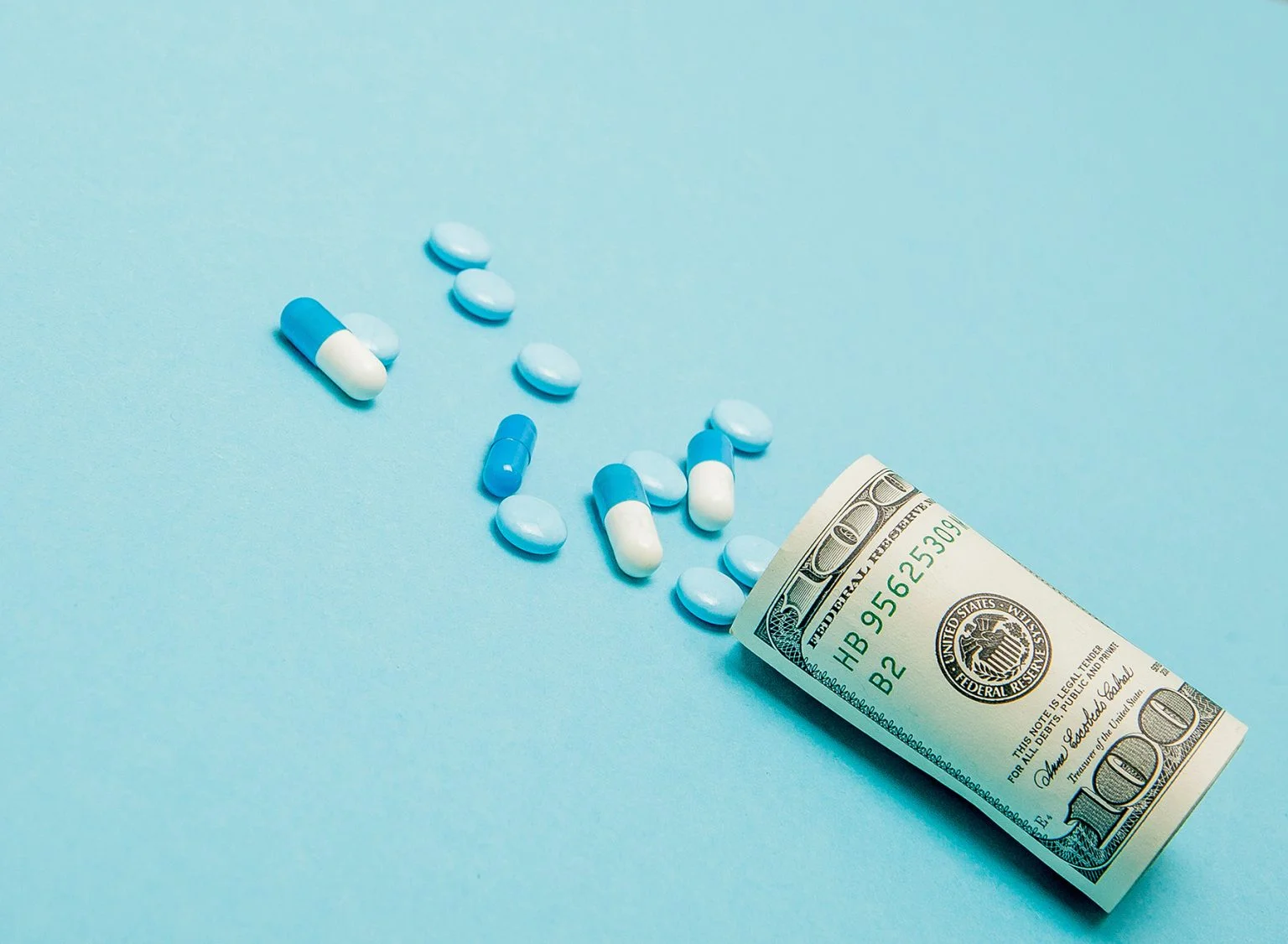 Money rolled up with pills flowing out isolated on blue background