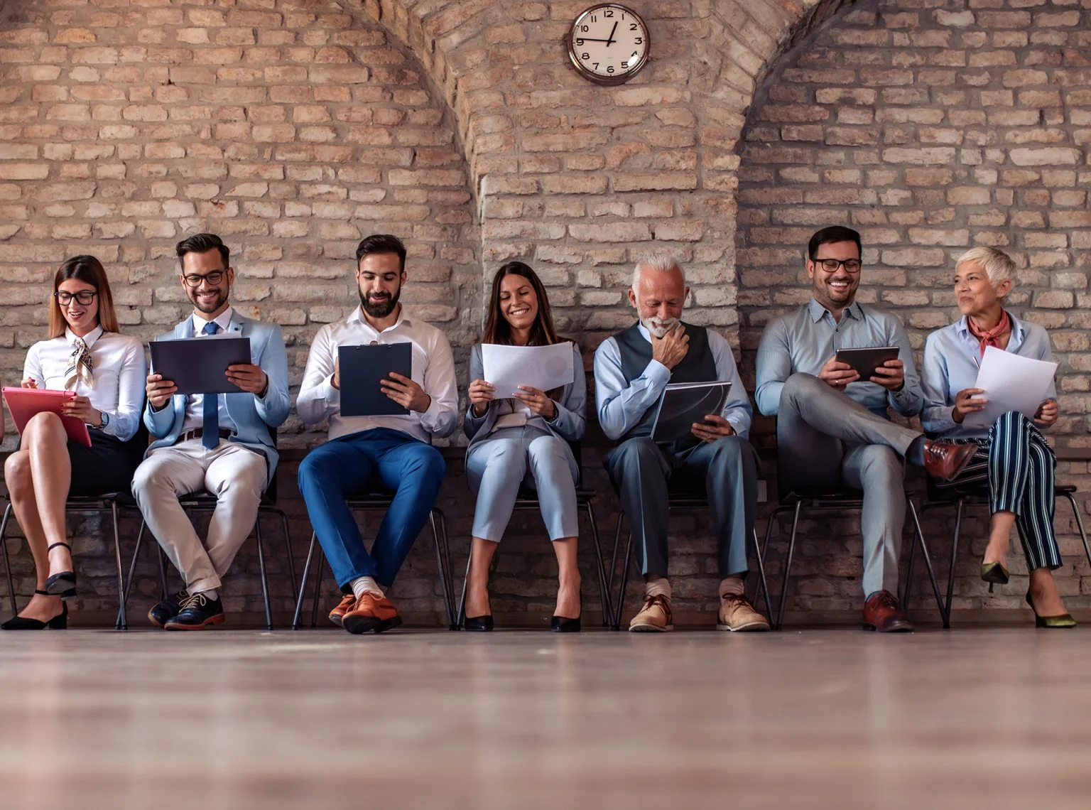 People sitting in chairs in a row waiting for job interview