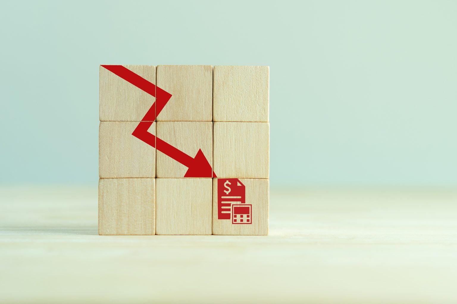Red arrow pointing down on wooden blocks towards money and calculator
