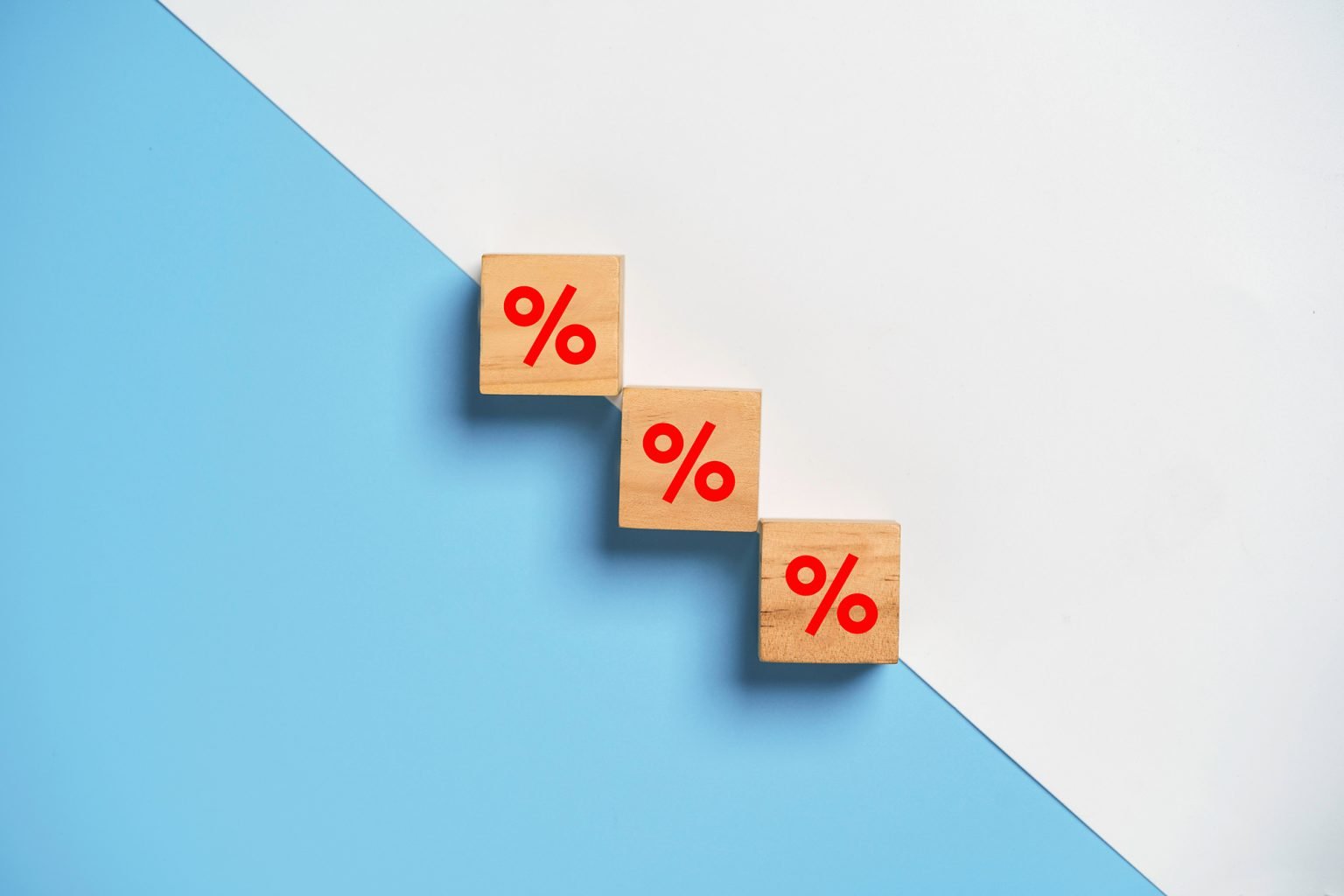 Red percentage sign print screen on wooden cube block on white and blue background for decrease financial interest rate concept