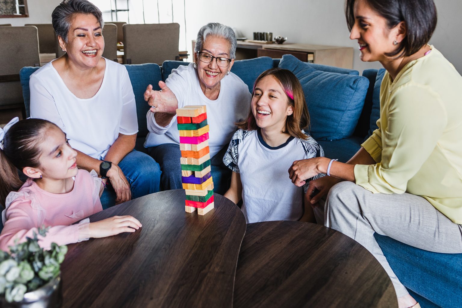 Three generations of women playing Jenga at a table