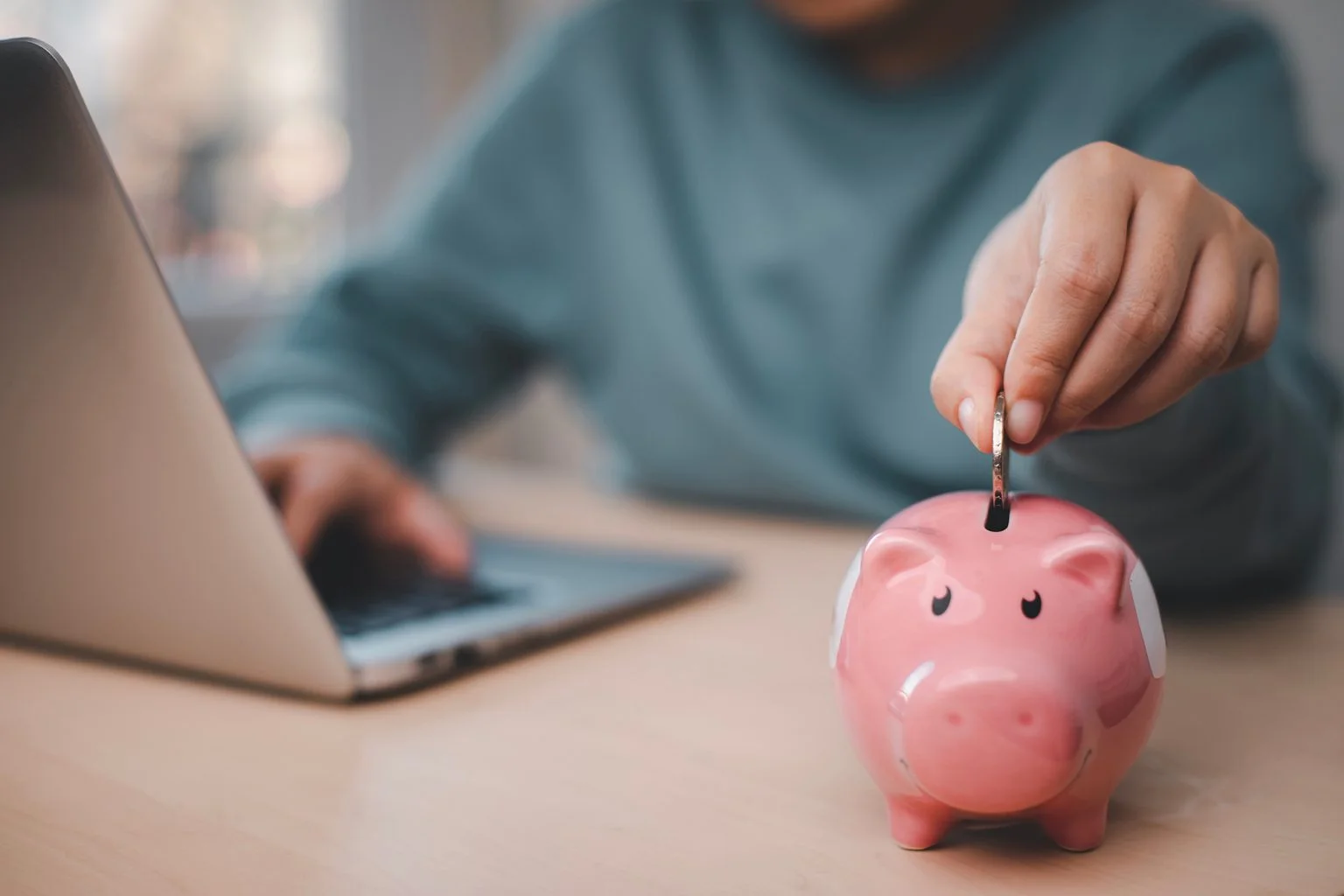 Woman hand putting coin in piggy bank