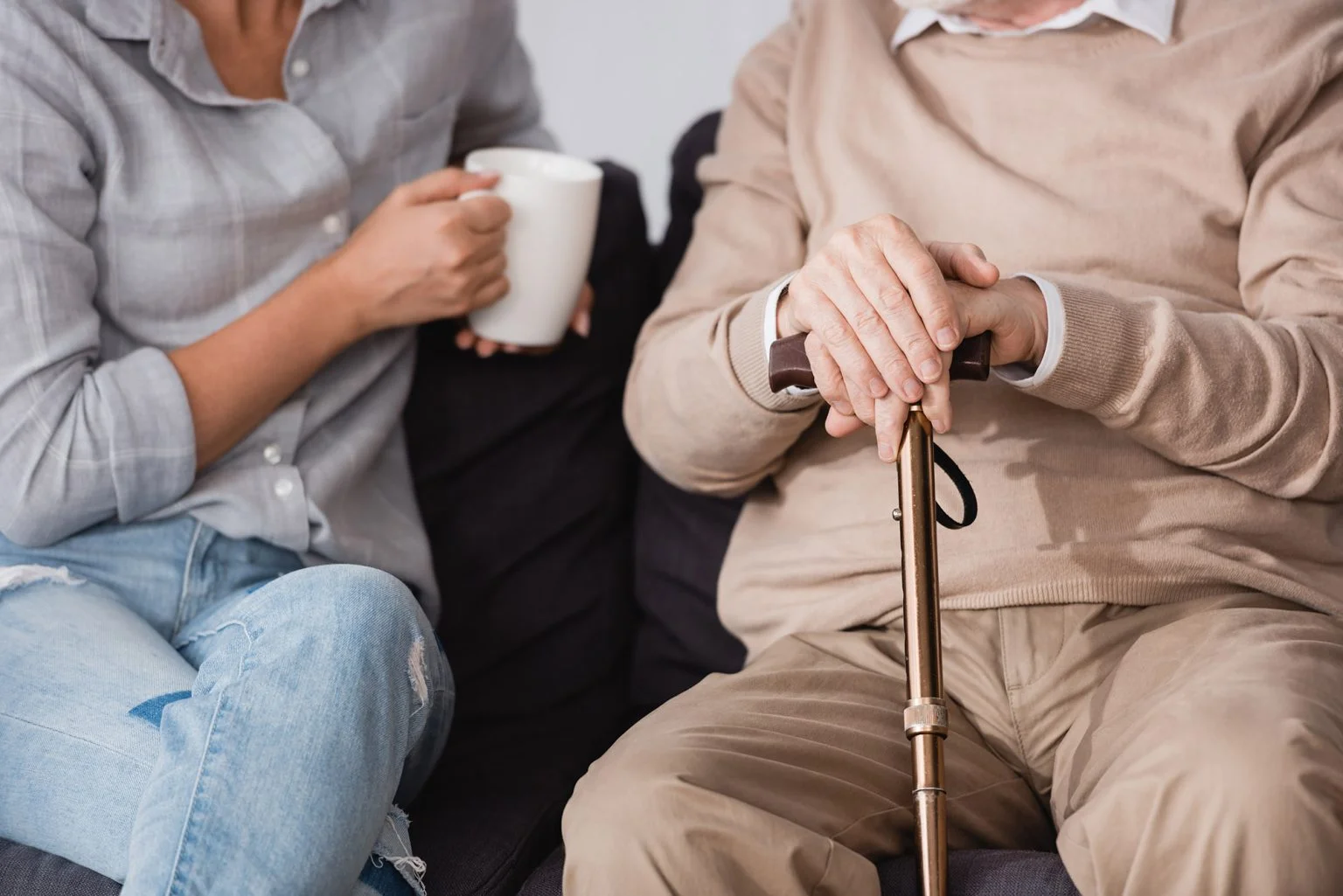 partial view of woman with cup of tea near aged father at home