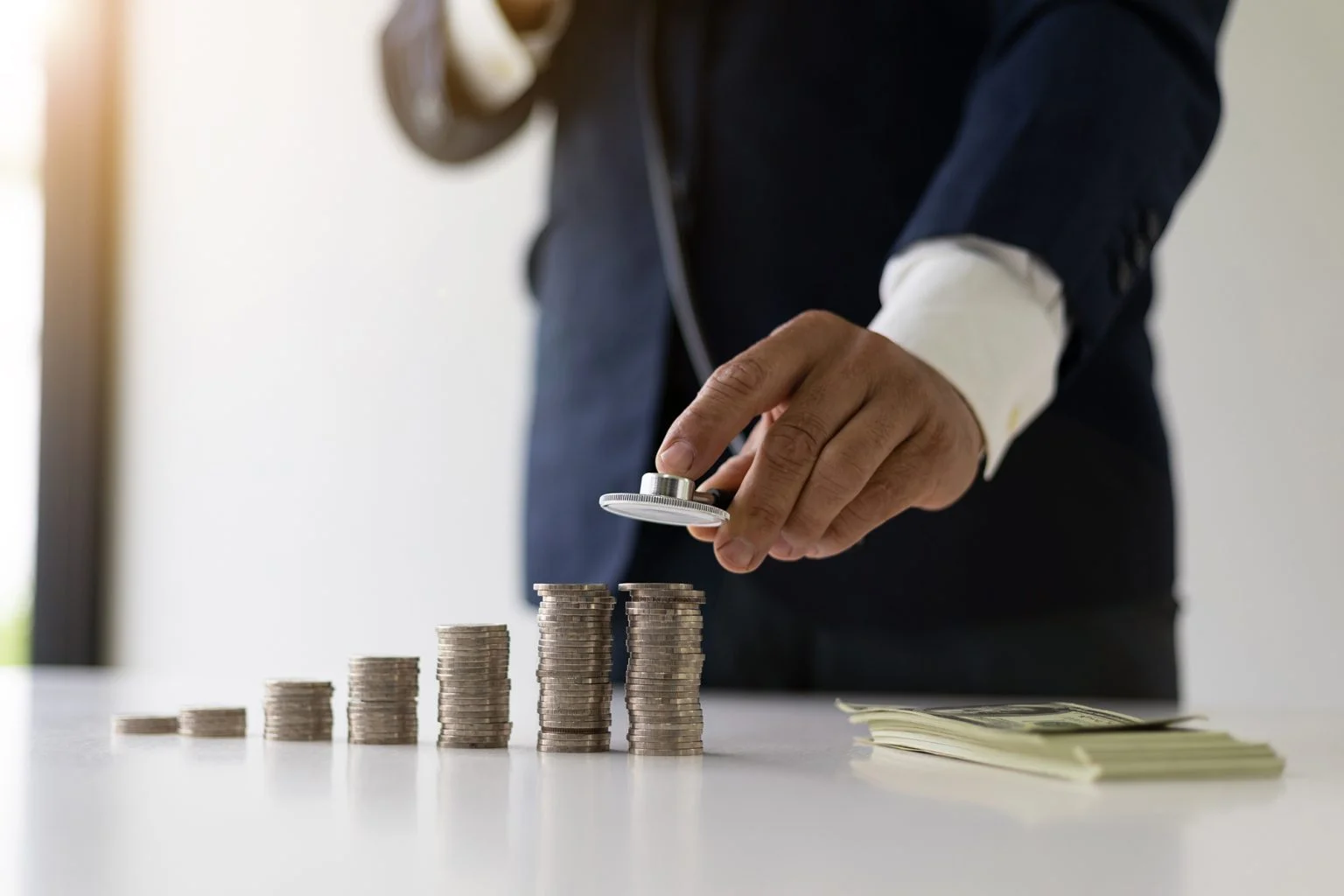 Doctor with a stethoscope checking increasing coin stacks