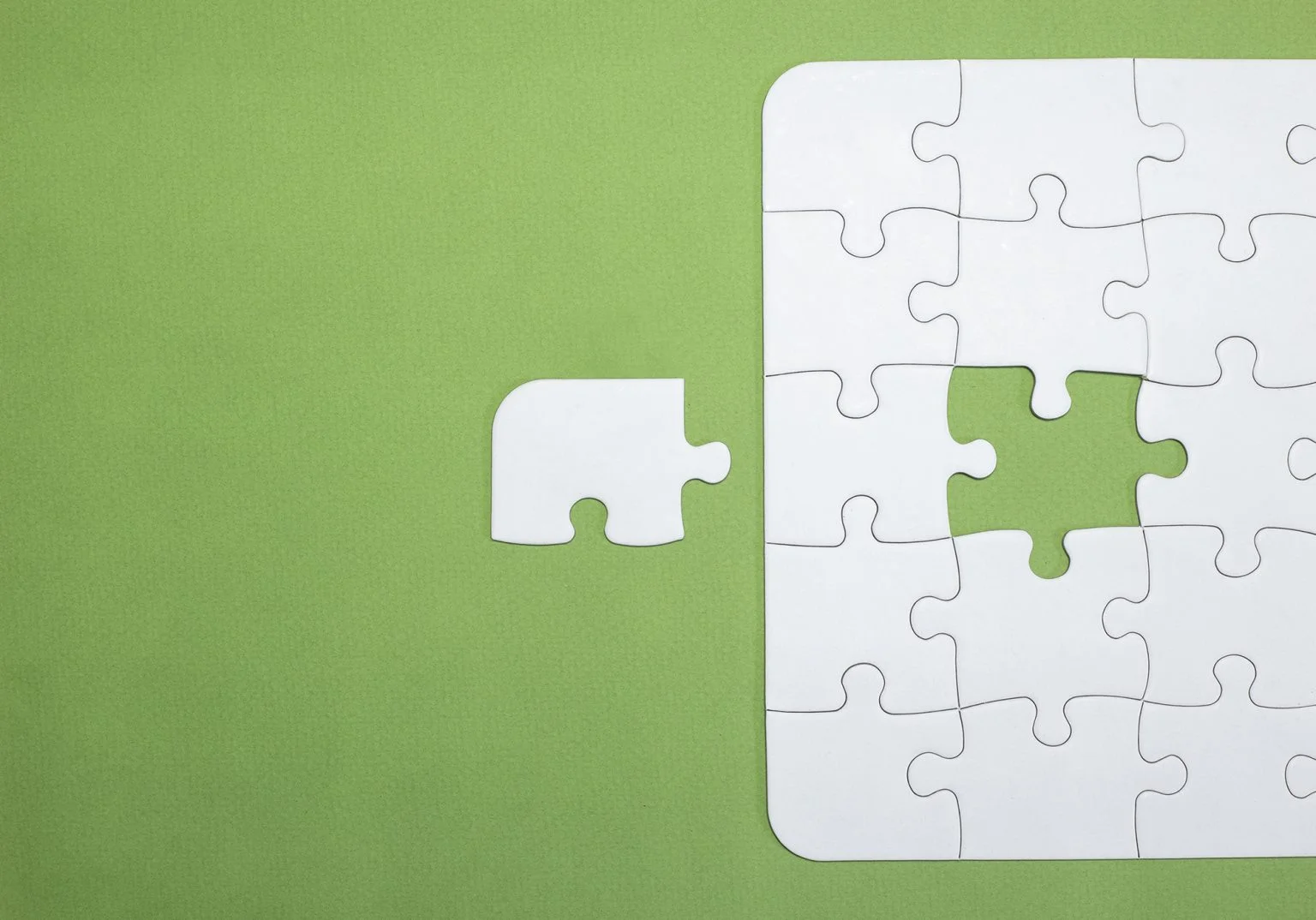White puzzle with a piece that doesn't fit on a green background