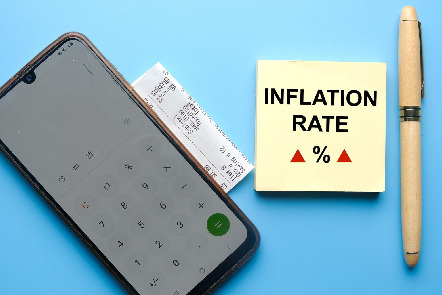 A picture of inflation rate word and notepad with pen, smartphone calculator and grocery receipt