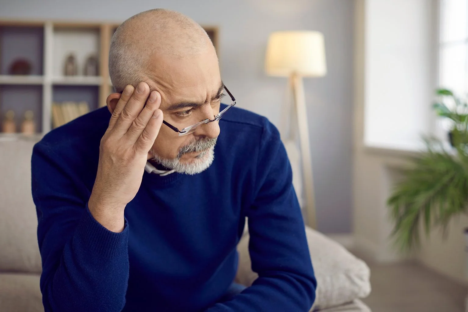 Close up head shot of man with glasses holding hand near his head