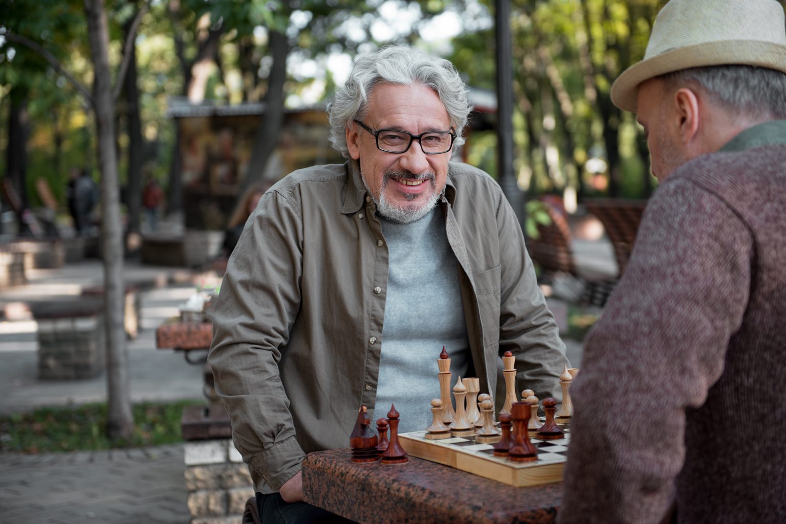 Joyful mature pensioners sitting at chessboard