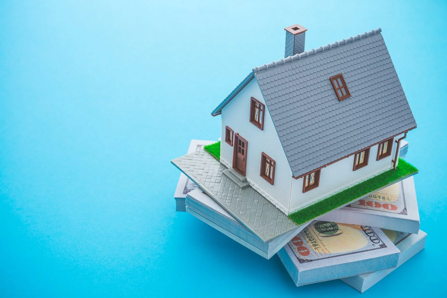 Model house and bank notes on a blue background