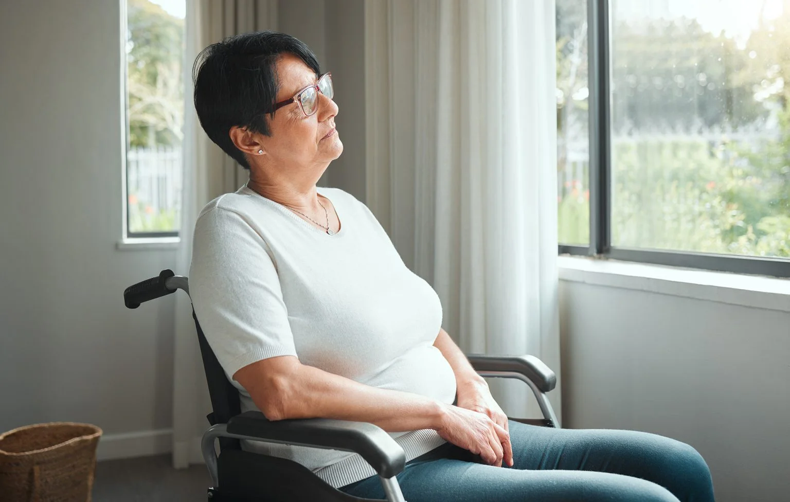 Portrait of a mature woman in a wheelchair looking out a window