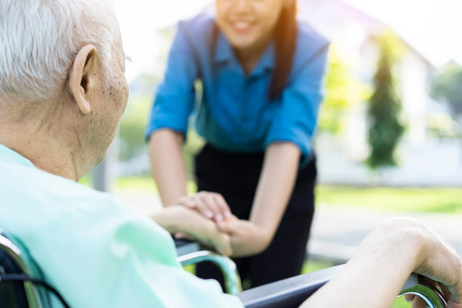 rear view of a man in wheel chair with a young woman leaning over to talk