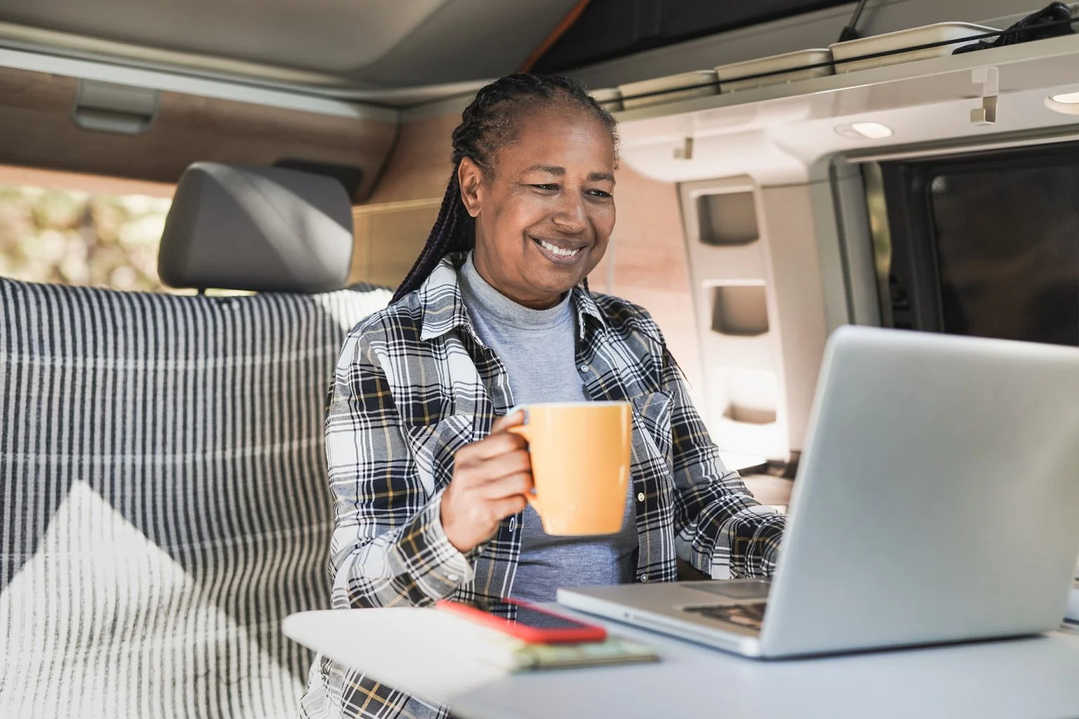senior woman using computer laptop inside mini van camper