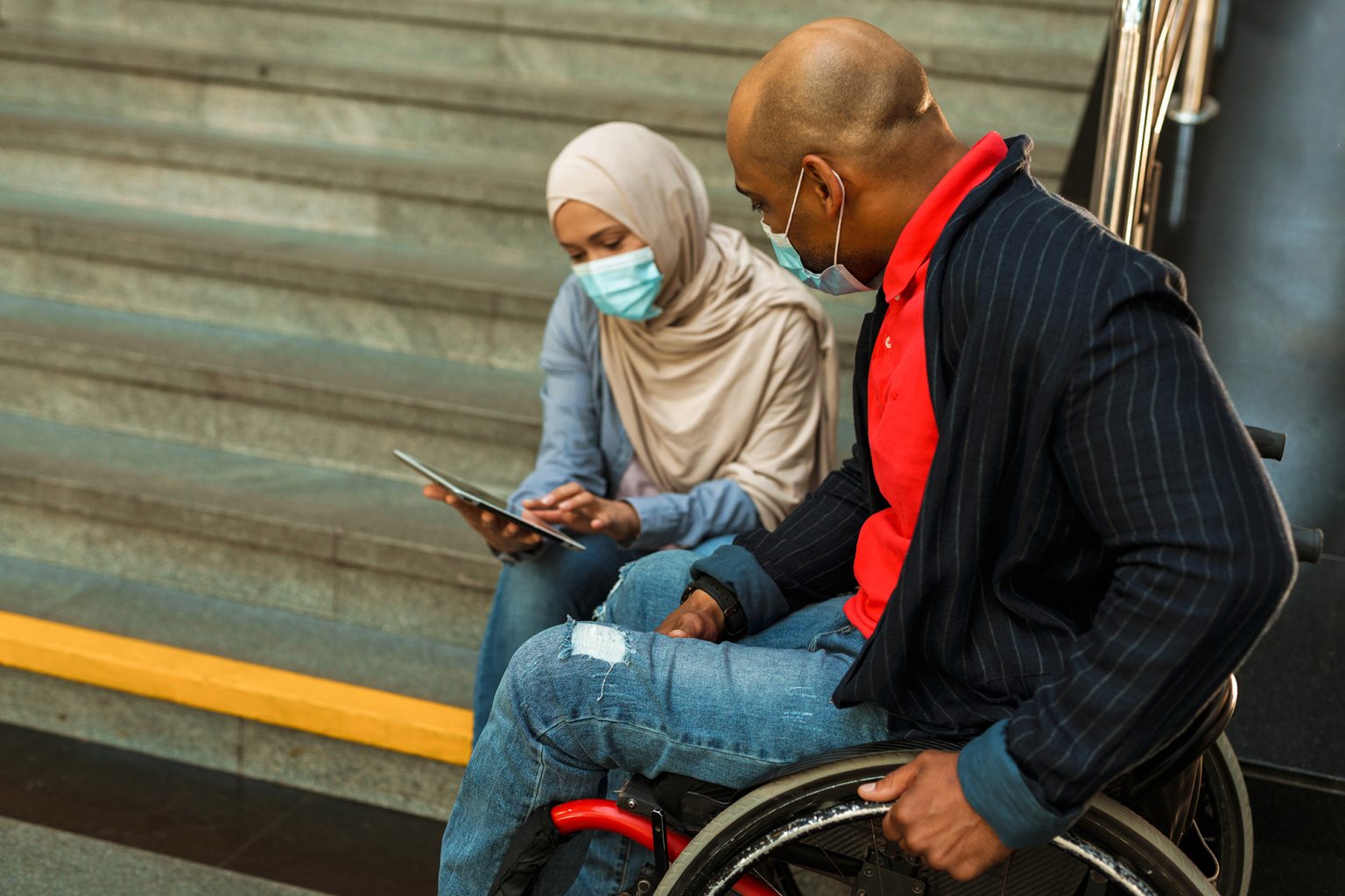 woman and disabled man in face mask using tablet computer together