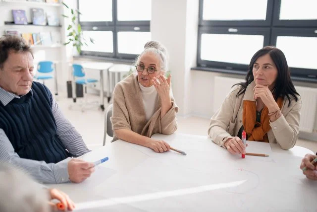 Older people discussing topic at a table in a classroom