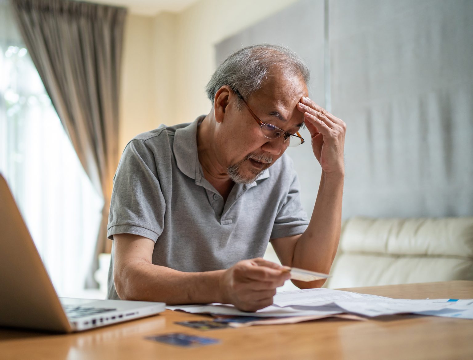 older man looking frustrated to paperwork and bills