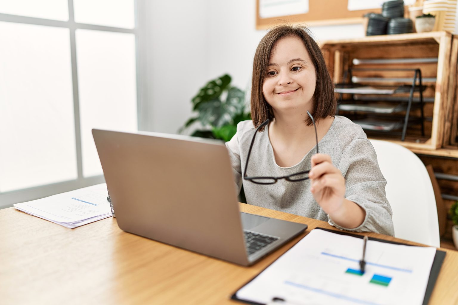 Brunette woman with down syndrome working using laptop at business office