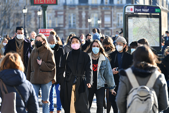 Crowd of people crossing street wearing COVID masks