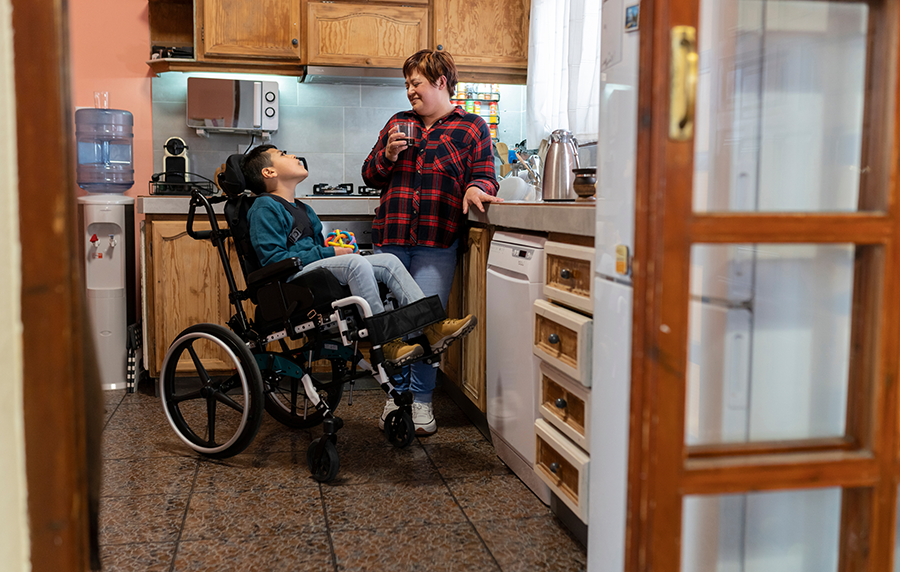 Latin mother drinking coffee in the kitchen with her disabled son