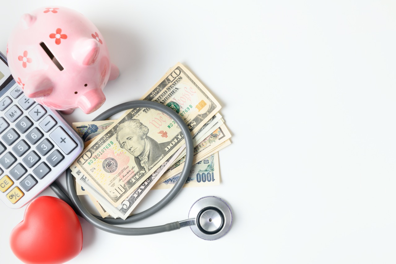 stethoscope on banknote and piggy bank on white background