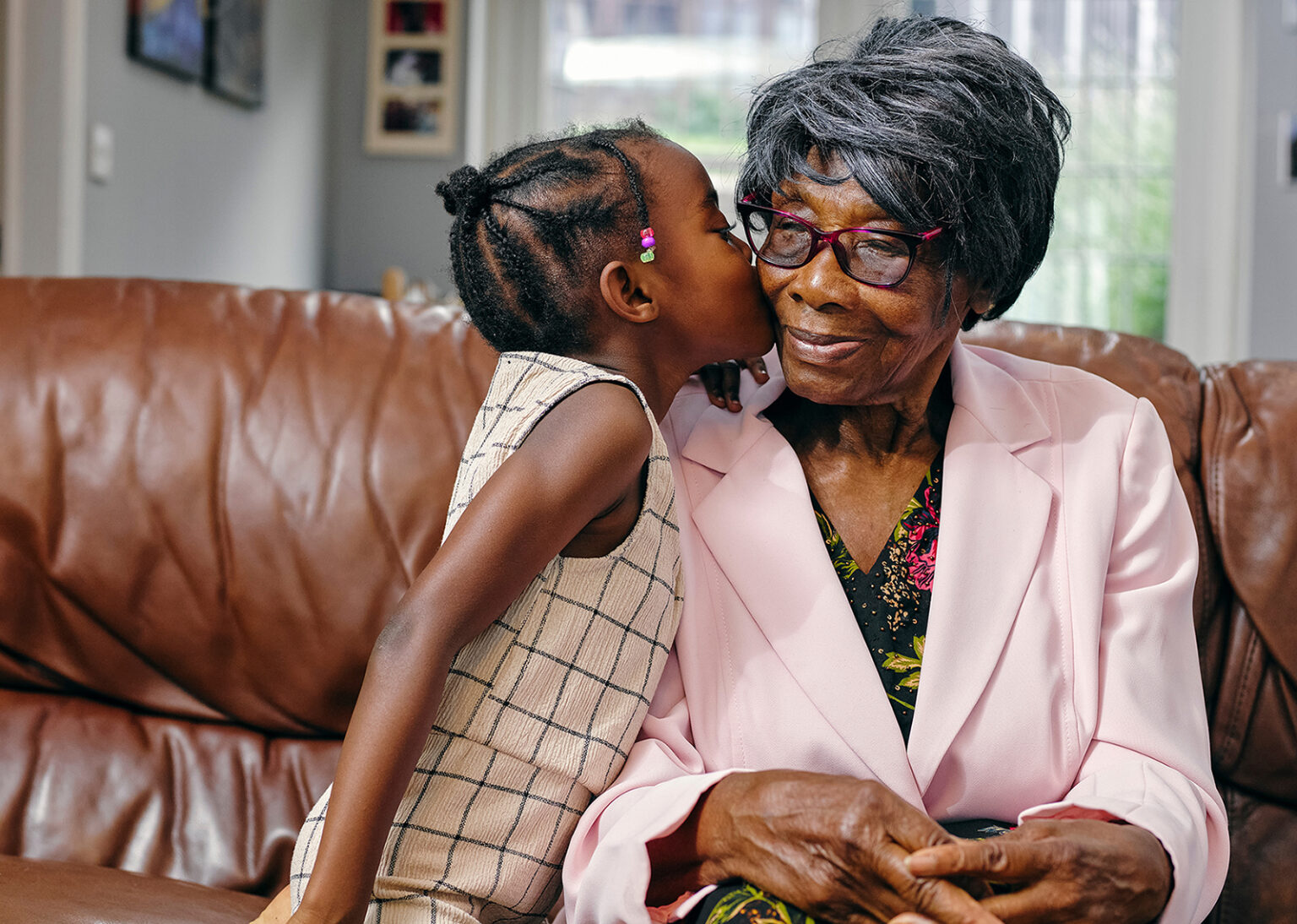 Great granddaughter kissing great grandmother on cheek