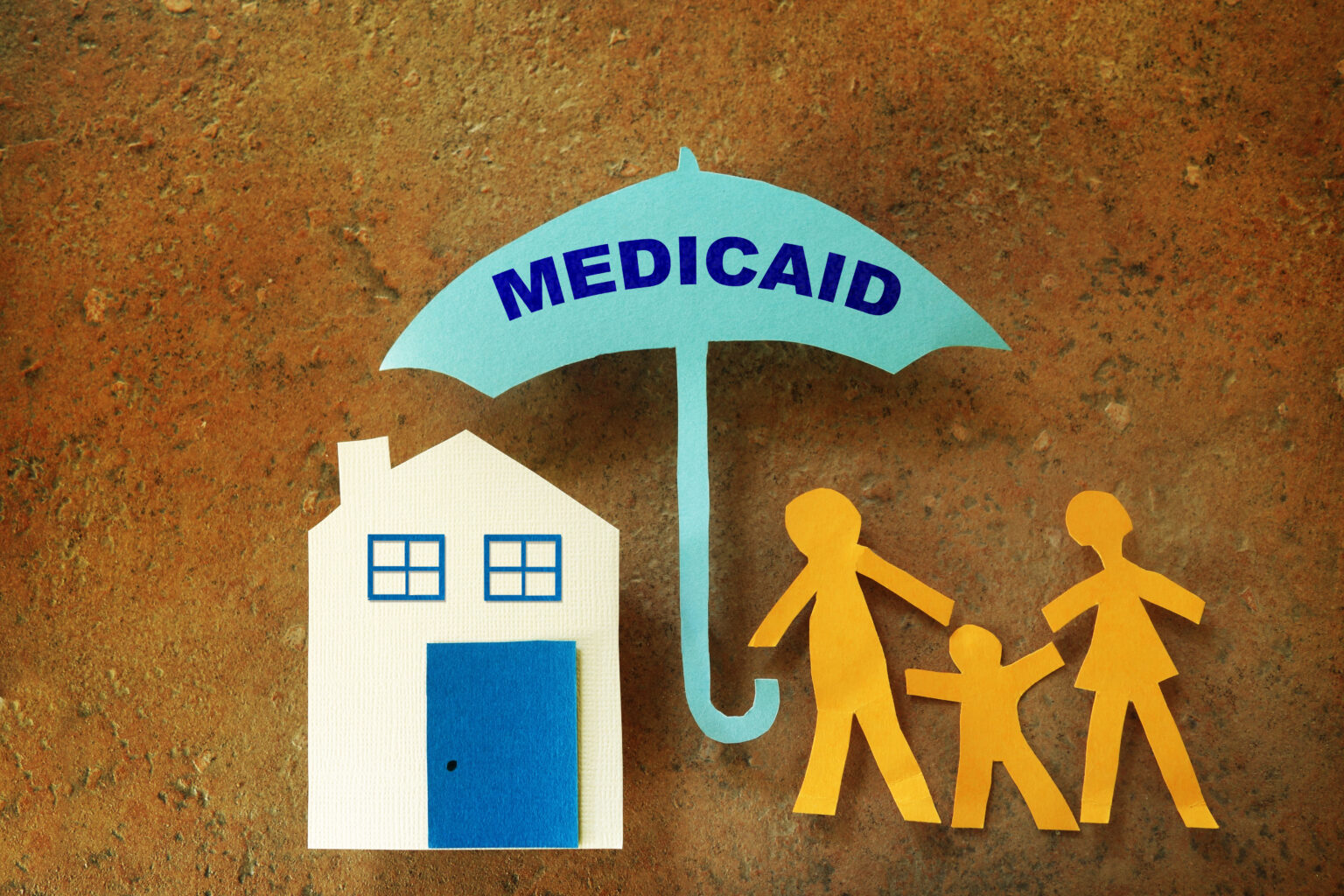 Paper cut outs of a family underneath an umbrella that says Medicaid