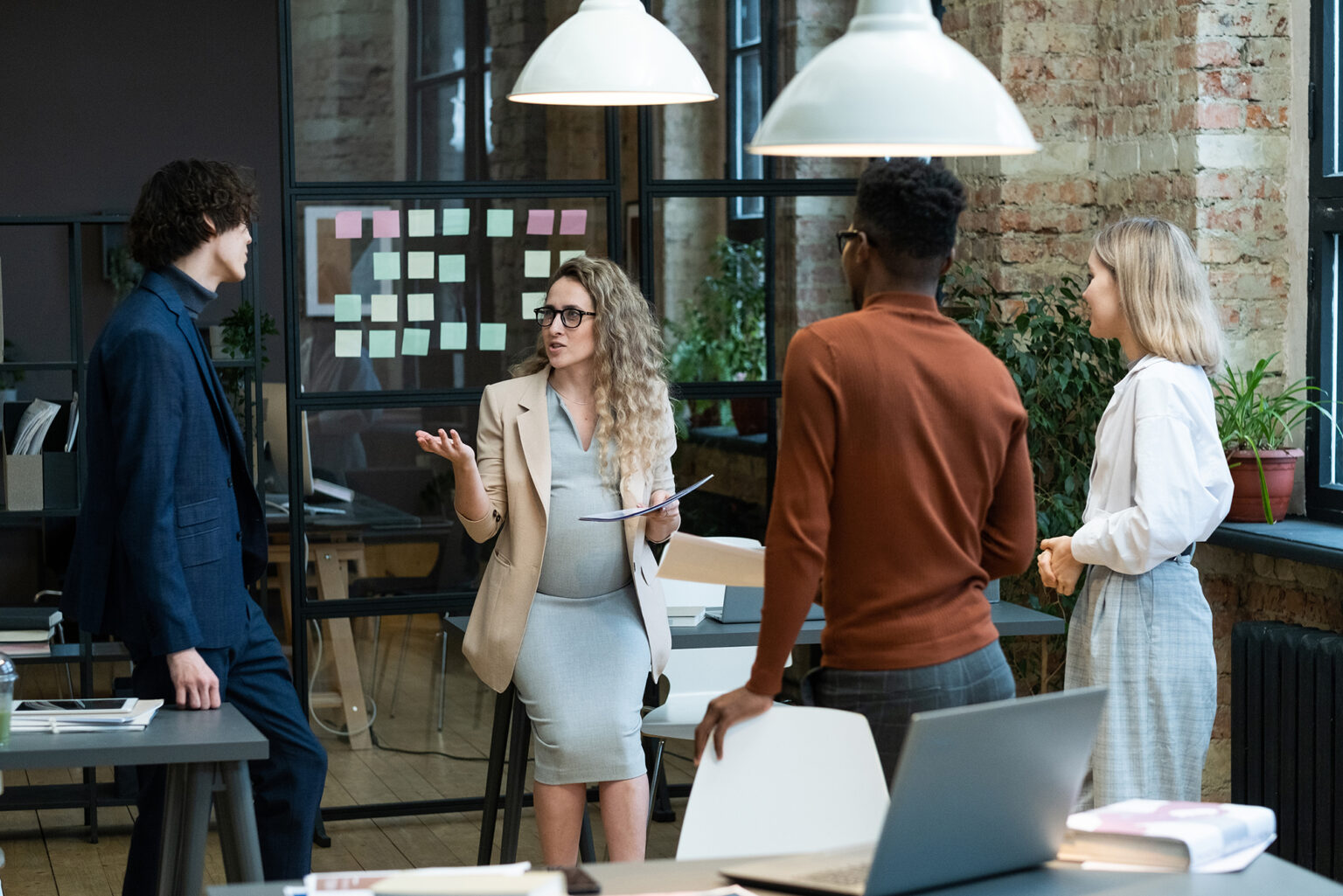 Pregnant businesswoman giving the tasks to employees before going to maternity leave, business people standing at office and listening to her