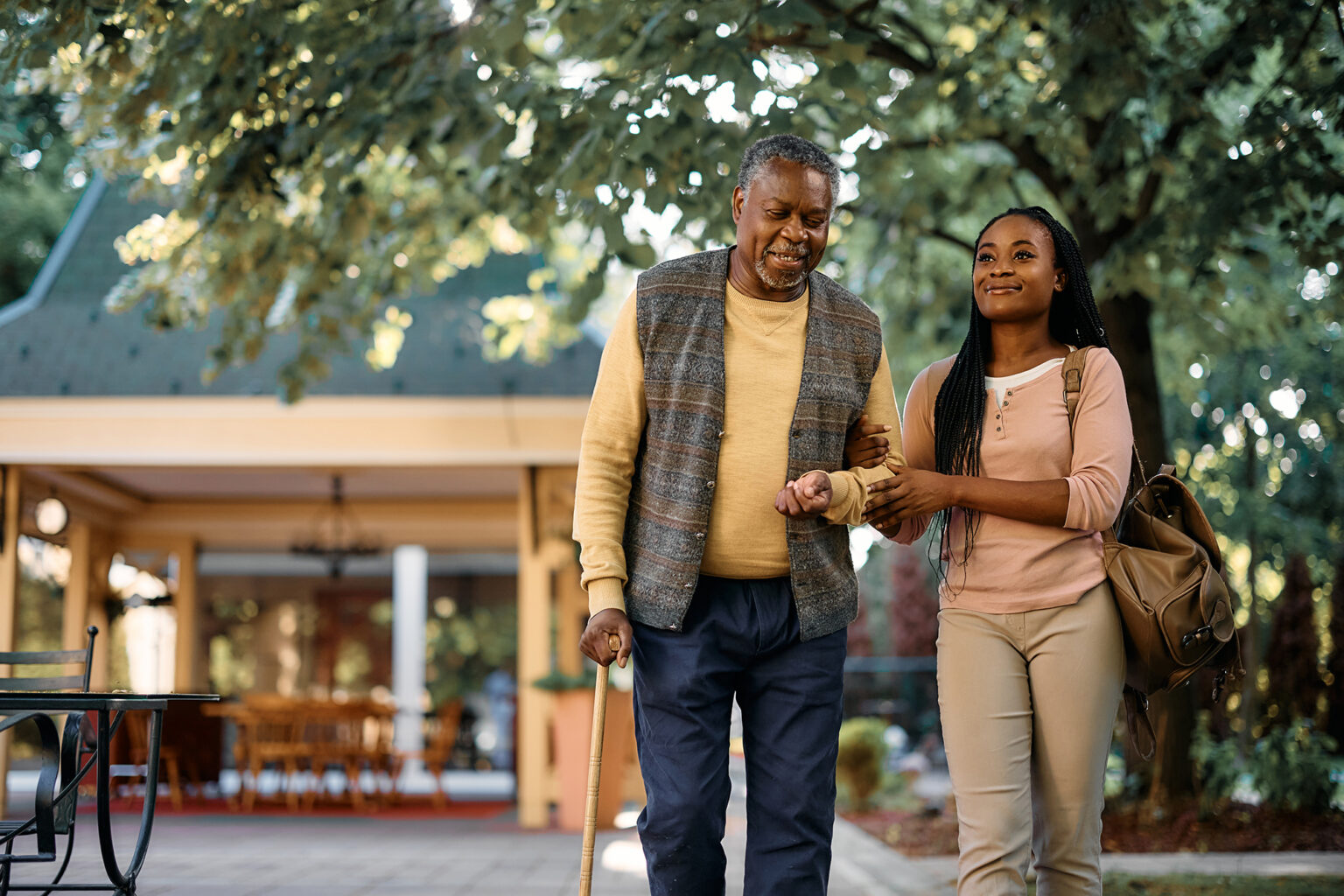 Daughter helping father using a cane walk outside