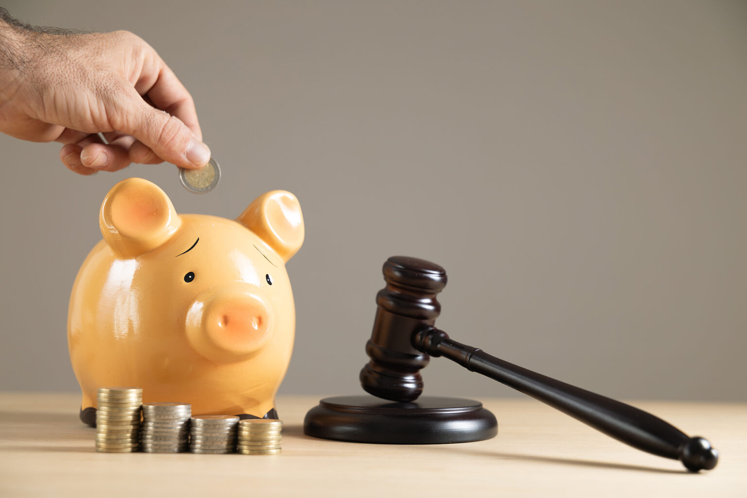 Close-up judge gavel with sad piggy bank and coun stacks