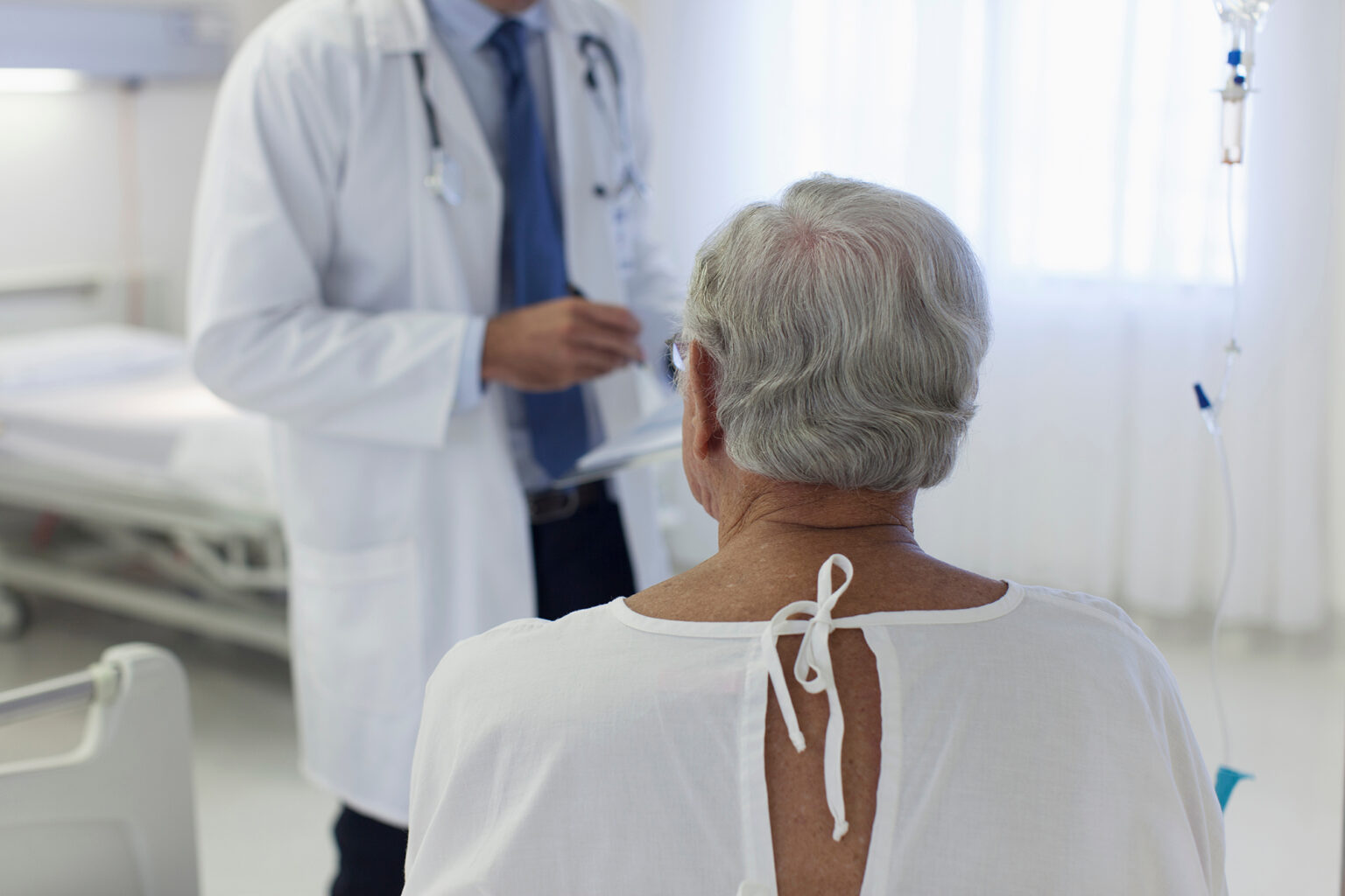 Male senior patient listening to doctor in hospital room