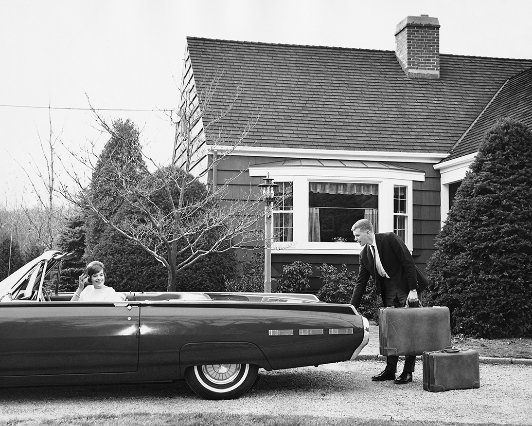 Man loading trunk with suitcases while woman waits in car stock photo