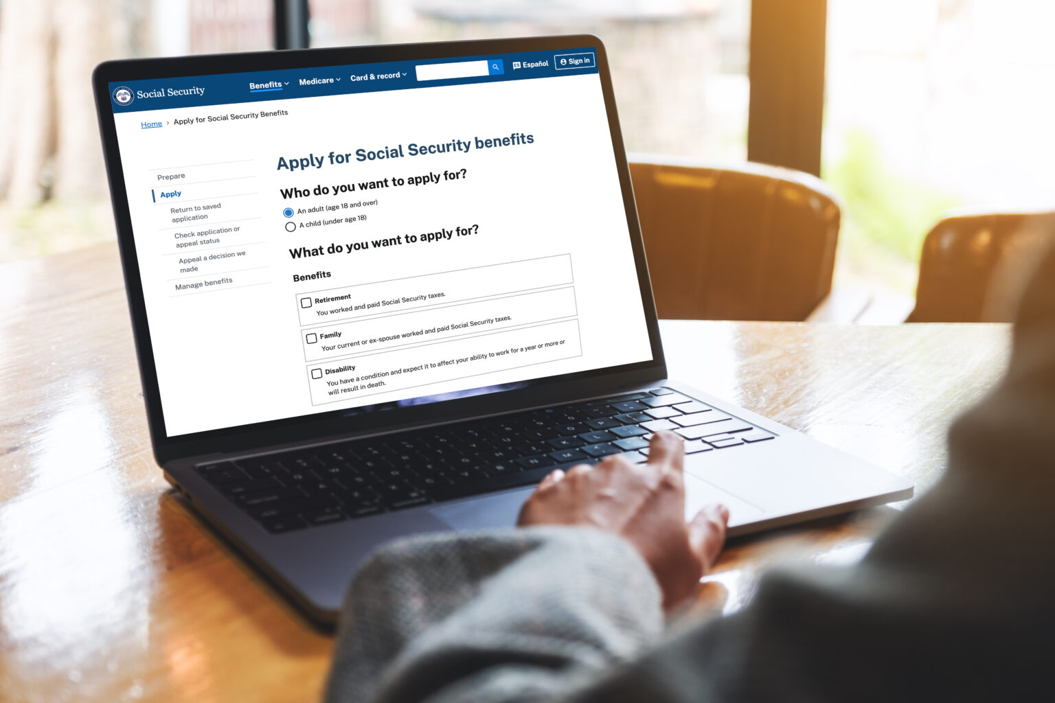 Laptop showing Social Security application form on a wooden table
